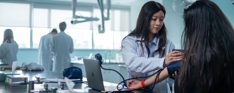 a Biomedical Sciences student measuring another student's blood pressure in a lab