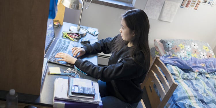 Student sitting at desk in dorm.
