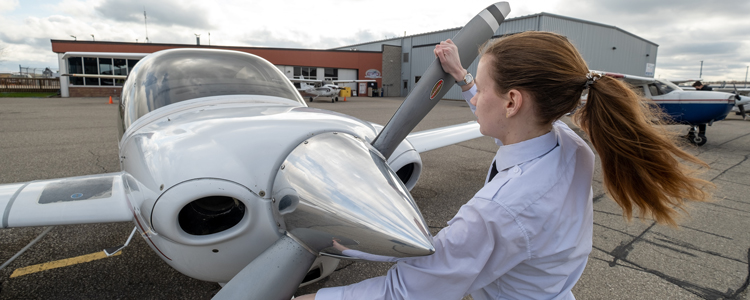 a Science and Aviation student adjusting the propeller on a plane