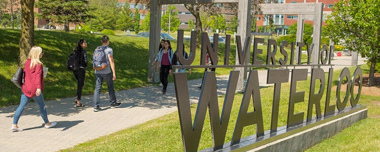 Students walking along path with big Waterloo sign in foreground