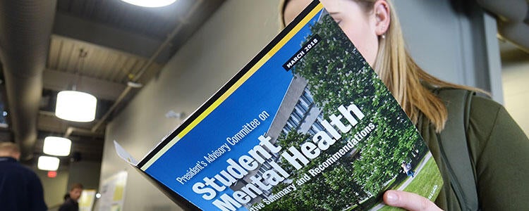 Waterloo student reading mental health brochure.