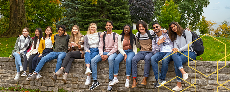 Group of students sitting on stone wall