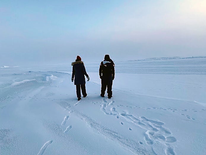 Aspiring geoscientist Becca and colleague walking across snow in the Arctic