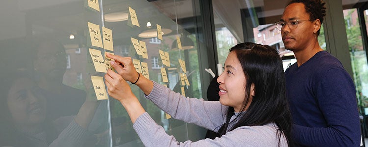 Business student putting sticky notes on a board