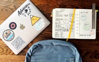 Laptop, backpack, and open notebook on wooden desk