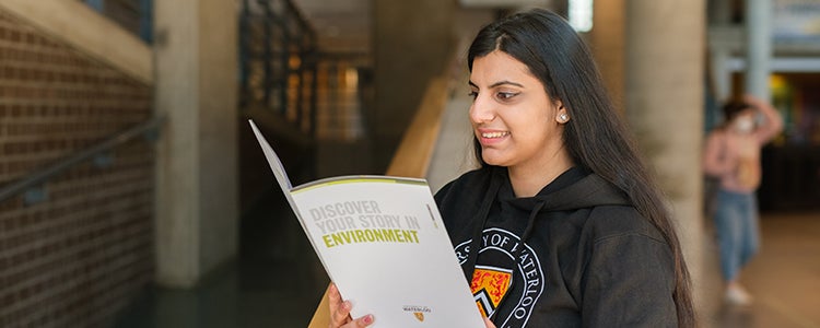 Student reading Waterloo's Environment program brochure.