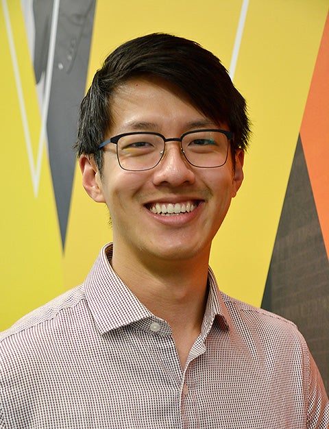 Evan Chang standing against a colourful background