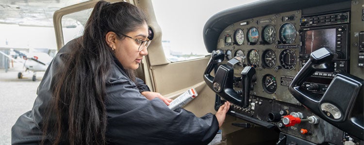 Geography and Aviation student inside a plane examining the controls