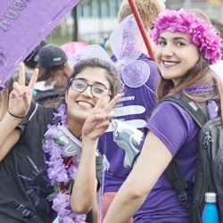 Two students wearing purple smile at the camera