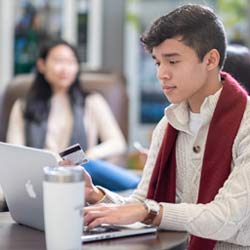 student sitting infront of laptop with credit card in hand