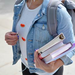 student carrying books with a backpack on