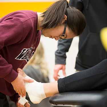 Faculty of Health Kinesiology student bandaging someone's foot