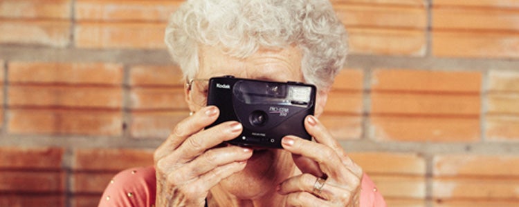 Elderly woman taking a photo with a disposable camera