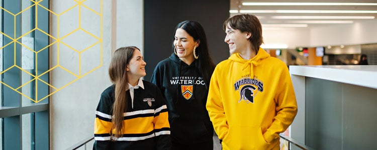 Three Indigenous students walking down a hallway together smiling