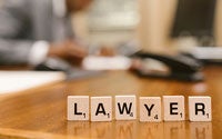 A lawyer in Canada working at their desk. Sitting on their desk are wooden block letters that spell out the word lawyer.