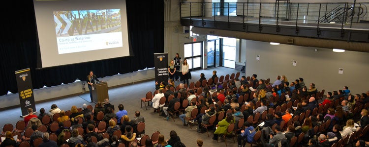Large lecture hall area filled with students watching a presentation at a Waterloo open house