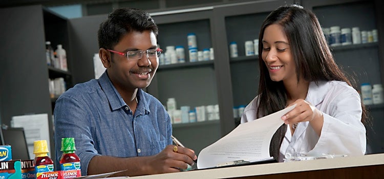 A student in the pharmacy degree program reviews paperwork with a prof 