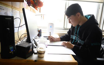 Student sitting at a desk, writing in a notebook