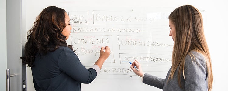 Two students writing on a whiteboard