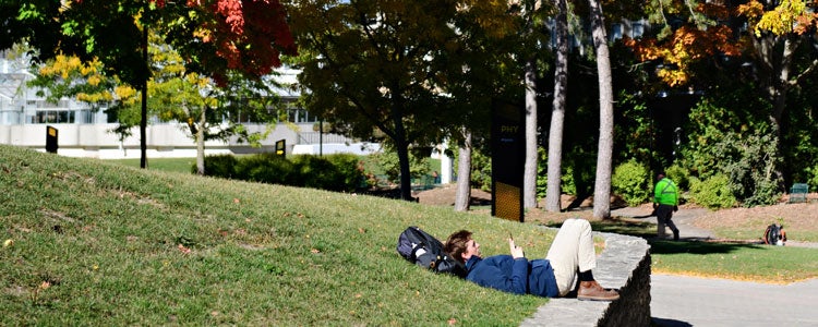 Student relaxing on a grass hill