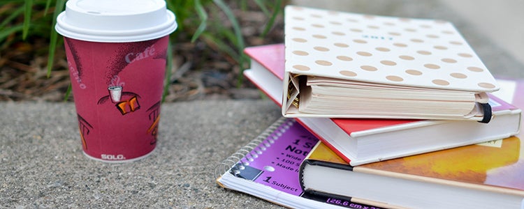 A cup of coffee next to a stack of textbooks