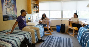 Three students in a traditional-style room with two beds