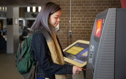 Girl using ATM machine.