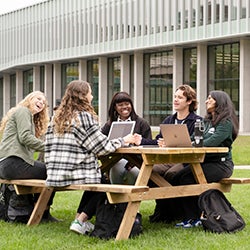 Five students sitting at a picnic bench