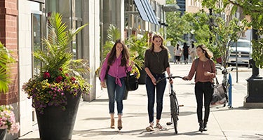 Three University of Waterloo students walking in uptown Waterloo with a bike