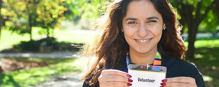 A student holding up a name tag that says volunteer