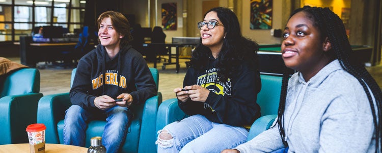 Three students playing video games together in residence