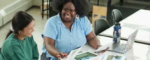 Two students laughing and doing school work together.