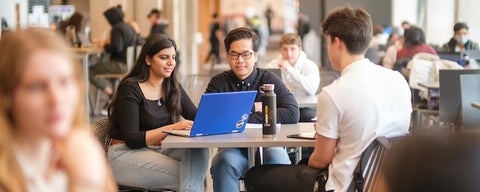 Waterloo students sitting in a cafeteria doing work.