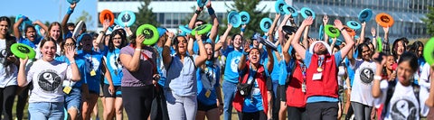 A large group of students outside with frisbees in hand