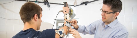 A researcher attaches sensors to a participant's arm in a lab