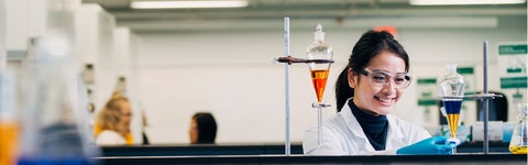 Student in white lab coat working in a lab