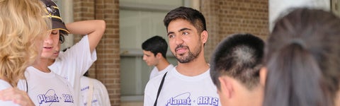 A group of art students together wearing arts merchandise and conversing during orientation.