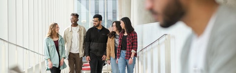 Five students walking along brightly lit hallways