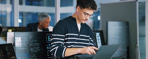A person working on a laptop in a tech office.