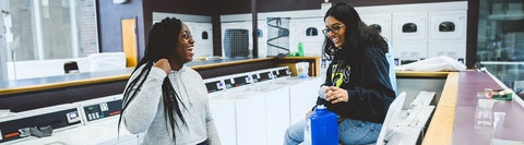 two students talking in a residence laundry room