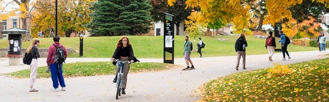 Students walking and cycling on the University of Waterloo campus in the fall