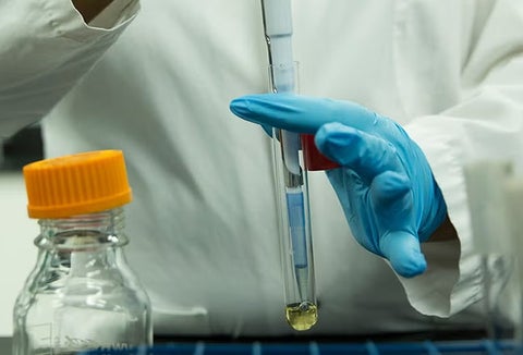 Someone in a lab coat and gloves using equipment.