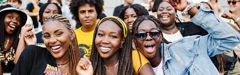 A groip of students smile excitedly on bleachers during Black and Gold day