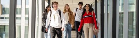 Five students walking down a hallway