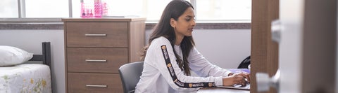 student sitting at a desk in their dorm room