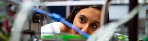 Student peering into a robotic project