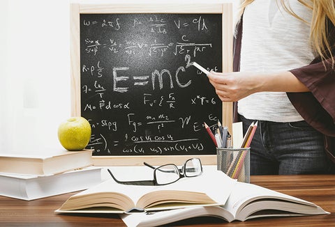 close up of student holding chalk in front of chalkboard with equations