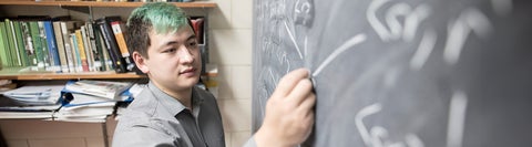 Student solving math equation on a chalkboard