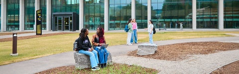 Students sit on bench outside the Student Life Centre at the University of Waterloo