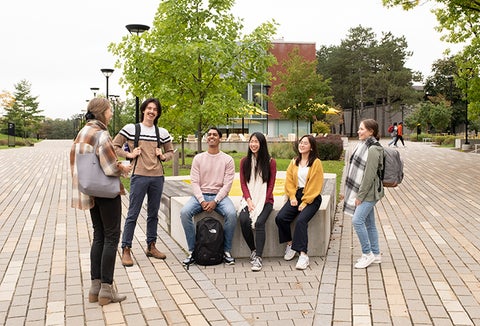 students sitting around talking on campus with brick pathway